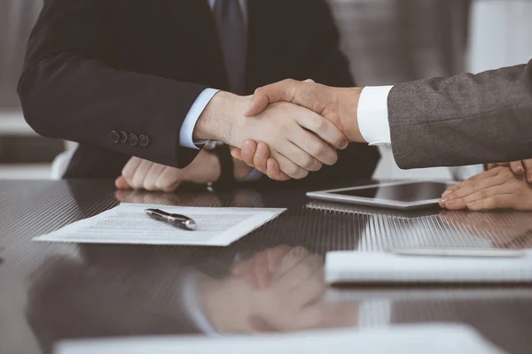 Handdruk als succesvol onderhandelingsresultaat, close-up. Onbekende zakenmensen schudden elkaar de hand na het tekenen van een contract in een modern kantoor — Stockfoto