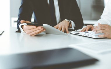Bilinmeyen iş adamları modern ofiste tablet bilgisayar kullanıyorlar. İş adamı ya da erkek girişimci, çalışma masasında meslektaşıyla birlikte çalışıyor.