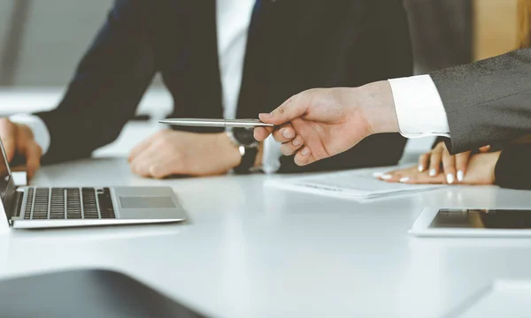 Empresarios y mujeres desconocidos sentados, usando computadora portátil y discutiendo preguntas en la reunión en la oficina moderna, primer plano — Foto de Stock