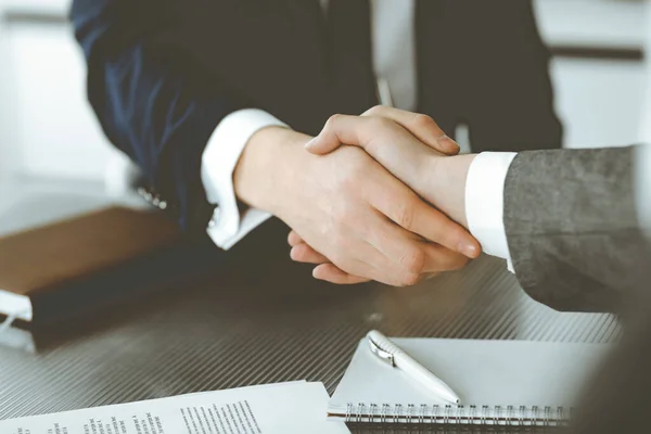 Onbekende zakenman schudt handen met zijn collega of partner boven het glazen bureau in modern kantoor, close-up. Zakenmensen groep op vergadering — Stockfoto