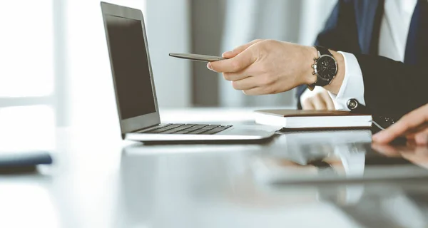 Empresarios y mujeres desconocidos sentados, usando computadora portátil y discutiendo preguntas en la reunión en la oficina moderna, primer plano — Foto de Stock