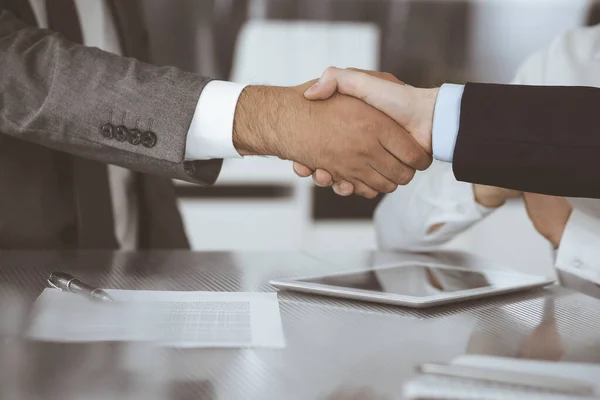 Handshake as successful negotiation ending, close-up. Unknown business people shaking hands after contract signing in modern office