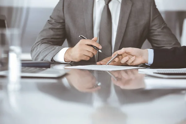 Des gens d'affaires inconnus qui travaillent ensemble à une réunion dans un bureau moderne, gros plan. Homme et femme d'affaires avec des collègues ou des avocats discutant du contrat lors de la négociation Photos De Stock Libres De Droits