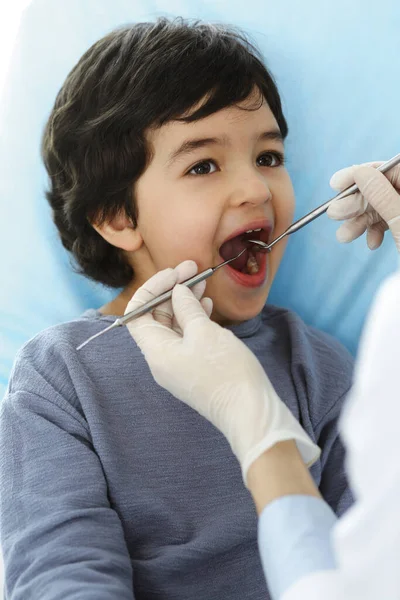 Küçük Arap çocuk dişçi doktoruna sözlü muayene sırasında ağzı açık bir şekilde dişçi koltuğunda oturuyor. Stomatoloji kavramı — Stok fotoğraf
