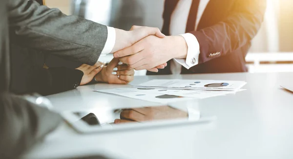 Unknown businessman shaking hands with his colleague or partner above the desk in sunny office, close-up — Stock Photo, Image