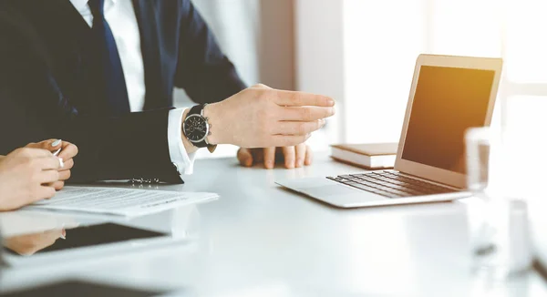 Empresarios y mujeres desconocidos sentados, usando computadora portátil y discutiendo preguntas en la reunión en la oficina soleada, de cerca. Concepto de éxito — Foto de Stock