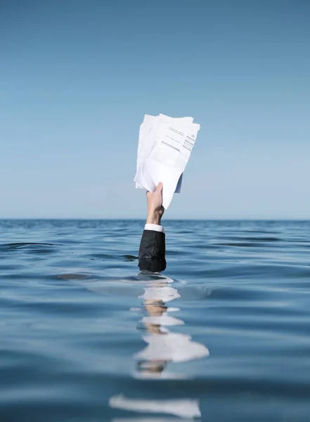 Seeking rescue. Businessman Drowning in The Sea with Documents in Hand.