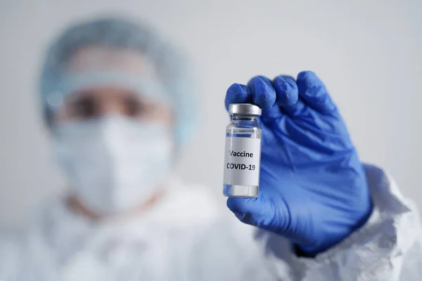 Koruyucu Giysi Doktoru Coronavirus Aşısıyla Ampul tutuyor COVID-19 virüsü için.. 