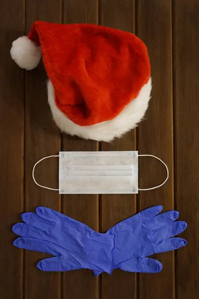 2020 Noeli için Kit, Santa Hat, Ahşap bir arka planda cerrahi maske ve eldivenler