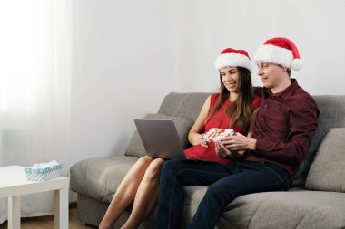 Genç bir çift Noel 'i evde kutluyor. Laptop 'tan Oturma ve Konuşan Online.