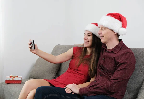 Genç bir çift Noel 'i evde kutluyor. Smartphone 'dan Oturma ve Konuşan Çevrimiçi.