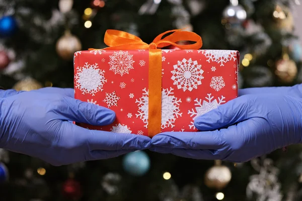 Arkaplanda Noel Ağacıyla Koruyucu Eldiven Kutusu Vermek