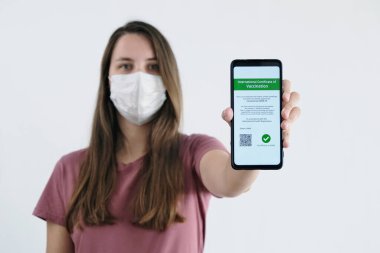 Yüz Maskeli Kadın Cep Telefonunda Aşı Sertifikası Gösteriyor