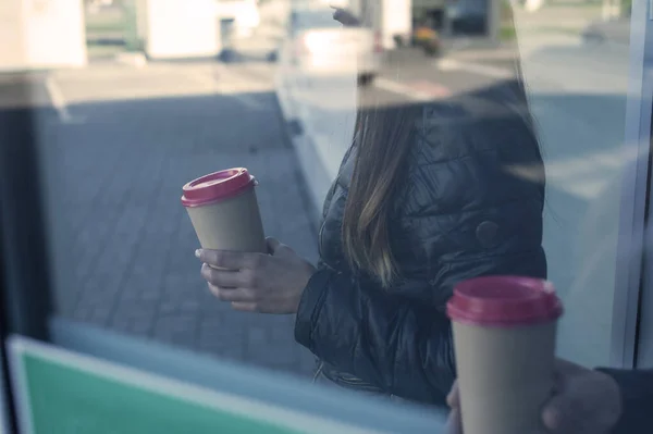 A girl and a guy are drinking coffee with a glass in their hands