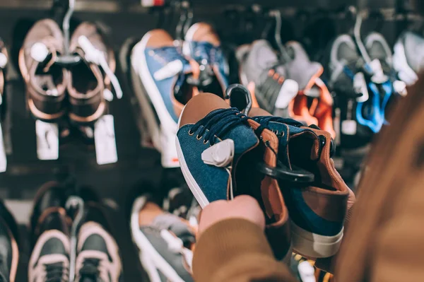 Adam süpermarkette spor ayakkabılarını tutuyor.