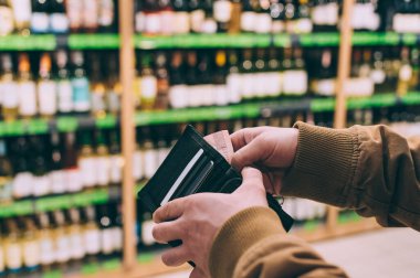 Adamın biri elinde dolarlarla süpermarketin arka planında bir cüzdan tutuyor.