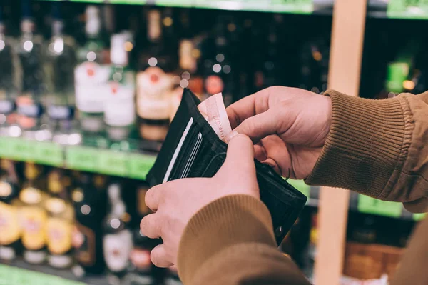 Adamın biri elinde dolarlarla süpermarketin arka planında bir cüzdan tutuyor.