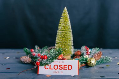 Üzgünüm, kapalıyız. Yeni yıl ve Noel için şenlikli kompozisyon. Tahta bir masanın üzerindeki süslemeli Noel ağacı