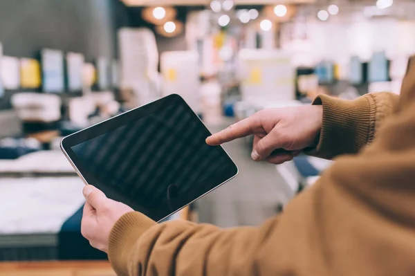 Mobilya dükkanında bir adam elinde bir tablet tutuyor.