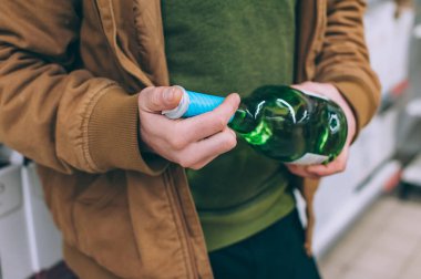 Süpermarkette alışveriş yapan biri elinde şarap tutuyor. Mal seçimi konusunda kavram