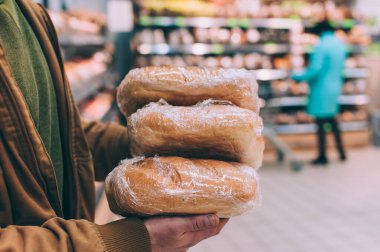 Süpermarkette alışveriş yapan biri elinde taze ekmek tutar.