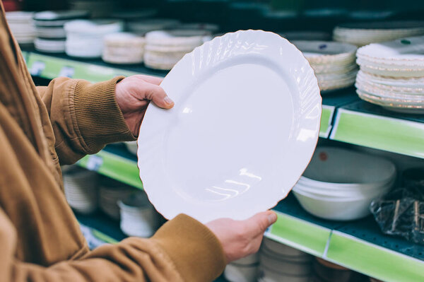 The guy in the supermarket is holding plates for food