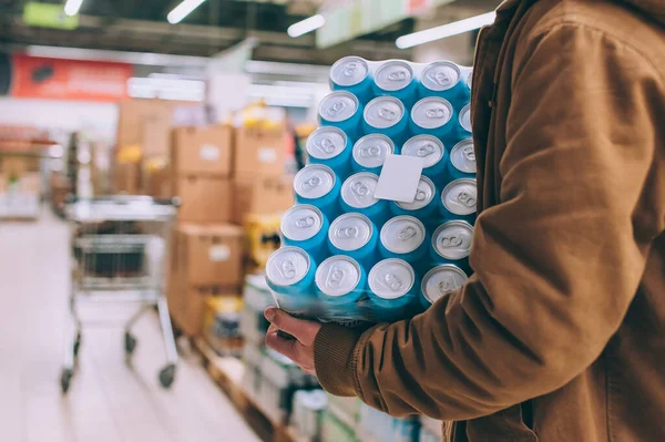 Süpermarkette alışveriş yapan biri elinde bir paket bira tutuyor.