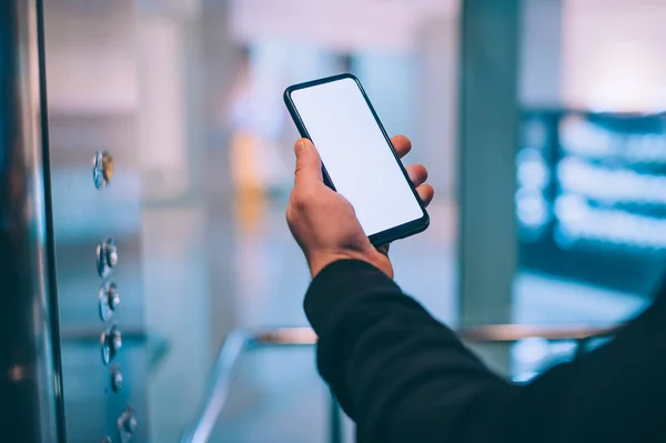 Model teknolojisi. Adam arka plandaki süpermarkette elinde akıllı bir telefon tutuyor.