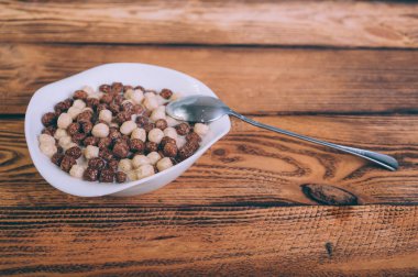 Tahta arka planda bir tabakta mısır gevreği.