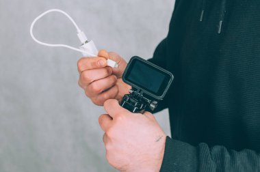 Bir adam hareket kamerasını taşınabilir şarj cihazıyla şarj ediyor.