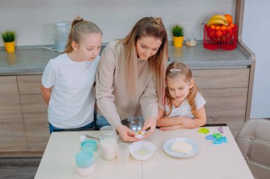 Annem kızlarına mutfakta hamur pişirmeyi öğretiyor.