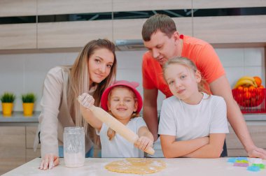 Annem ve babam iki kızıma mutfakta hamur pişirmeyi öğretiyor.