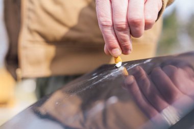 Adamın biri çöpte sigara söndürüyor.