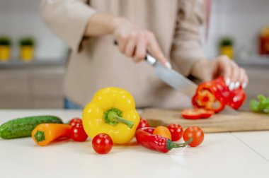 Kadın mutfakta olgun sebzeler kesiyor.