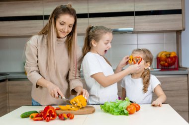 Anne ve kızları olgun sebzeleri kesiyorlar.