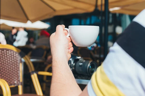Photographer man drinks coffee in a restaurant on the background of a table with a camera