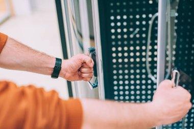 Hırdavatçıda bir adam evi için bir duş kabini seçer.