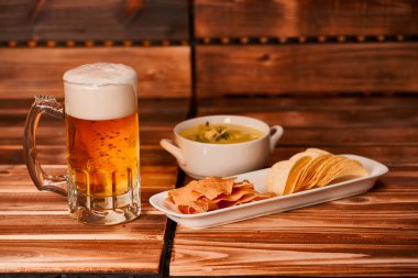 Bir bardak bira, patates kızartması ve sebze soslu abur cubur. Yeşil guacamole ile aperatif kupa ya da yarım litre bira. Kapat.,