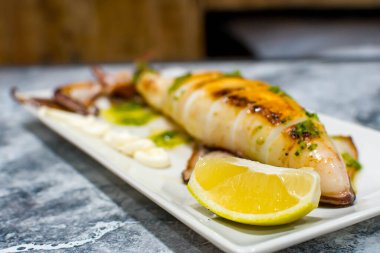 Yağlı, maydanozlu ve limonlu ızgara mürekkep balığı.