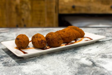 Tabakta sos olan kızarmış kroketler.