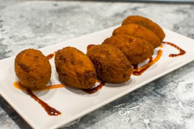 Tabakta sos olan kızarmış kroketler.