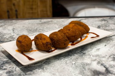 Tabakta sos olan kızarmış kroketler.