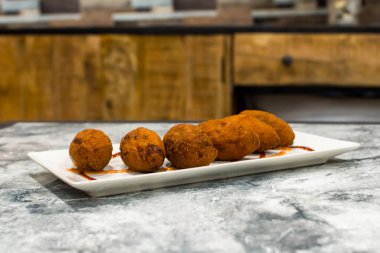 Tabakta sos olan kızarmış kroketler.