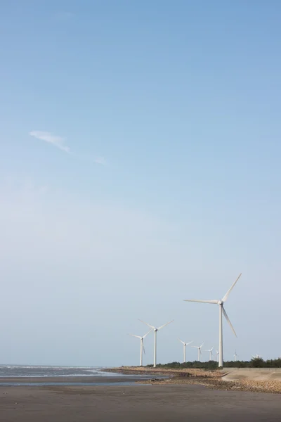 Ветровые турбины на берегу моря против голубого неба — стоковое фото