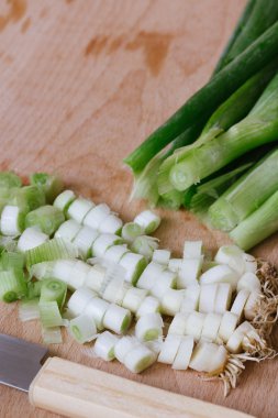 ahşap kesme tahtası üzerinde kıyılmış yeşil soğan