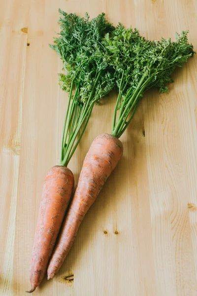 Fresh organic carrots with leaves on wooden background — Stock Photo, Image