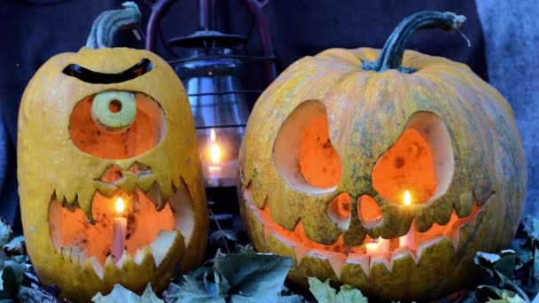 Video zu Halloween. zwei schreckliche Kürbisse gegen trockene Blätter und eine Öllampe — Stockvideo