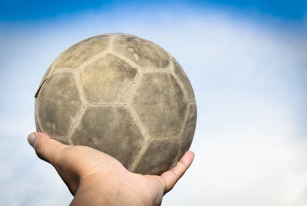 Old soccer ball in hand and blue sky — Stock Photo, Image