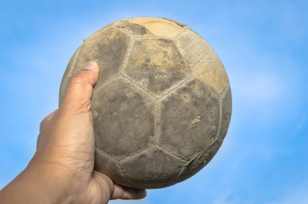 Bola de fútbol vieja en la mano y cielo azul — Foto de Stock