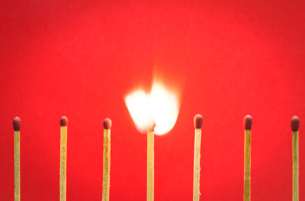 Burned match setting on red background for ideas and inspiration